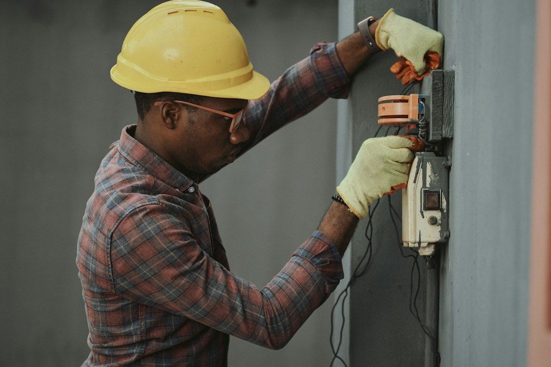Électricien en casque de chantier intervenant sur un compteur