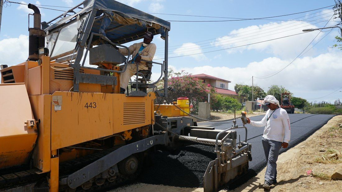 Engin de revêtement routier et technicien sur une chaussée en travaux