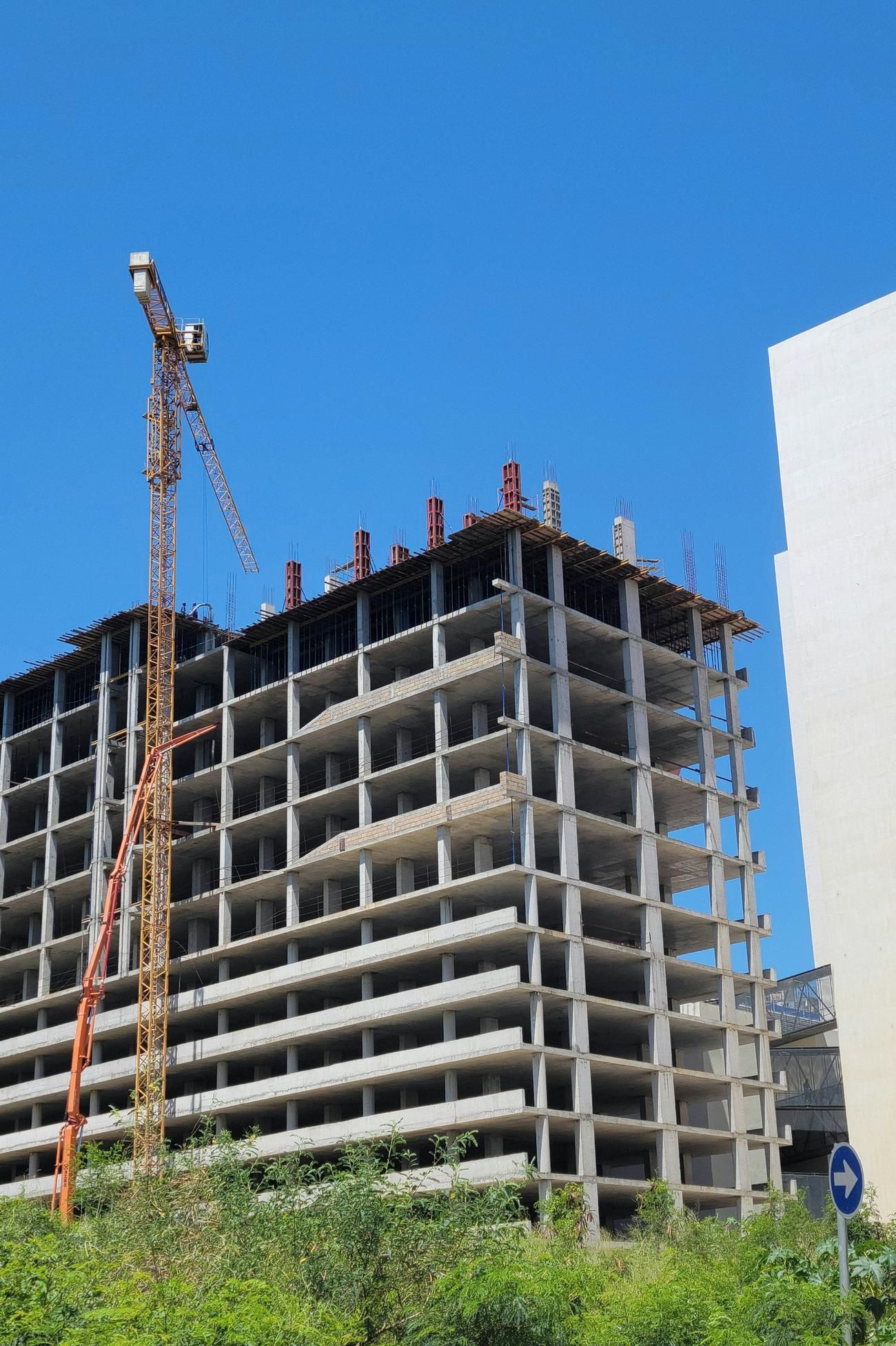 Immeuble en construction avec une grue à tour sous un ciel bleu